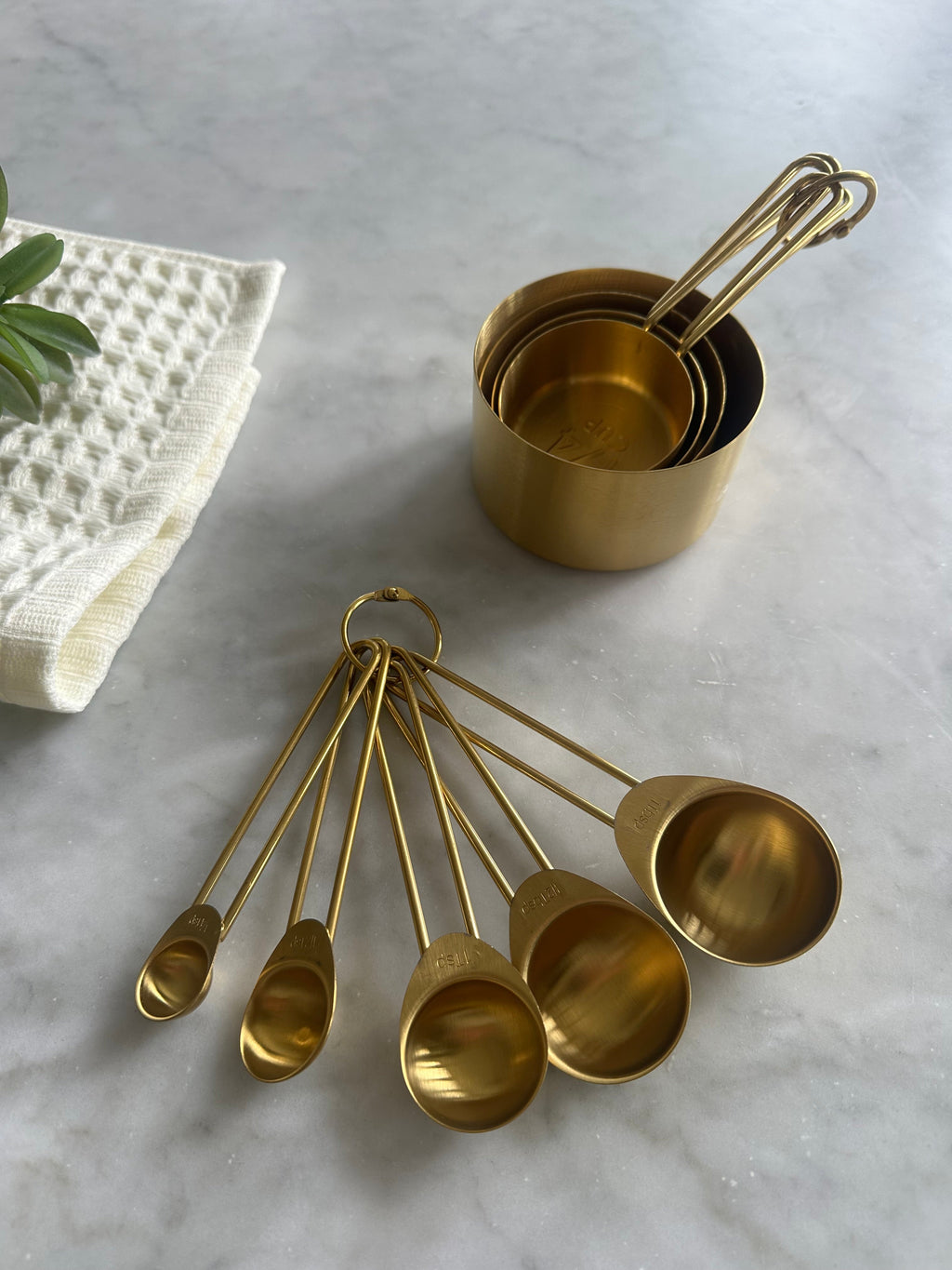 Nested gold measuring cups beside five matching measuring spoons
