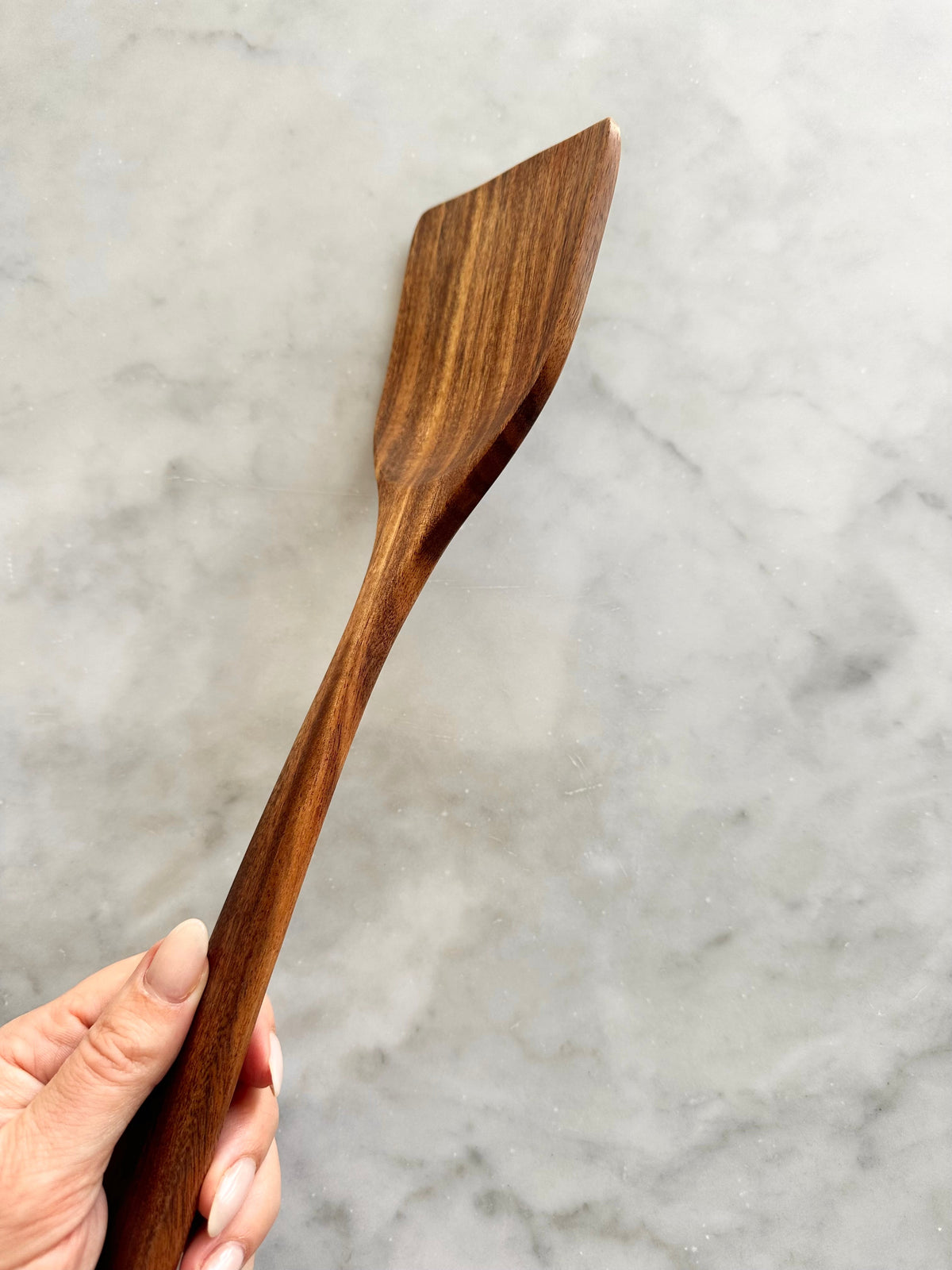 Side profile of a teak wood utensil with a flat working end