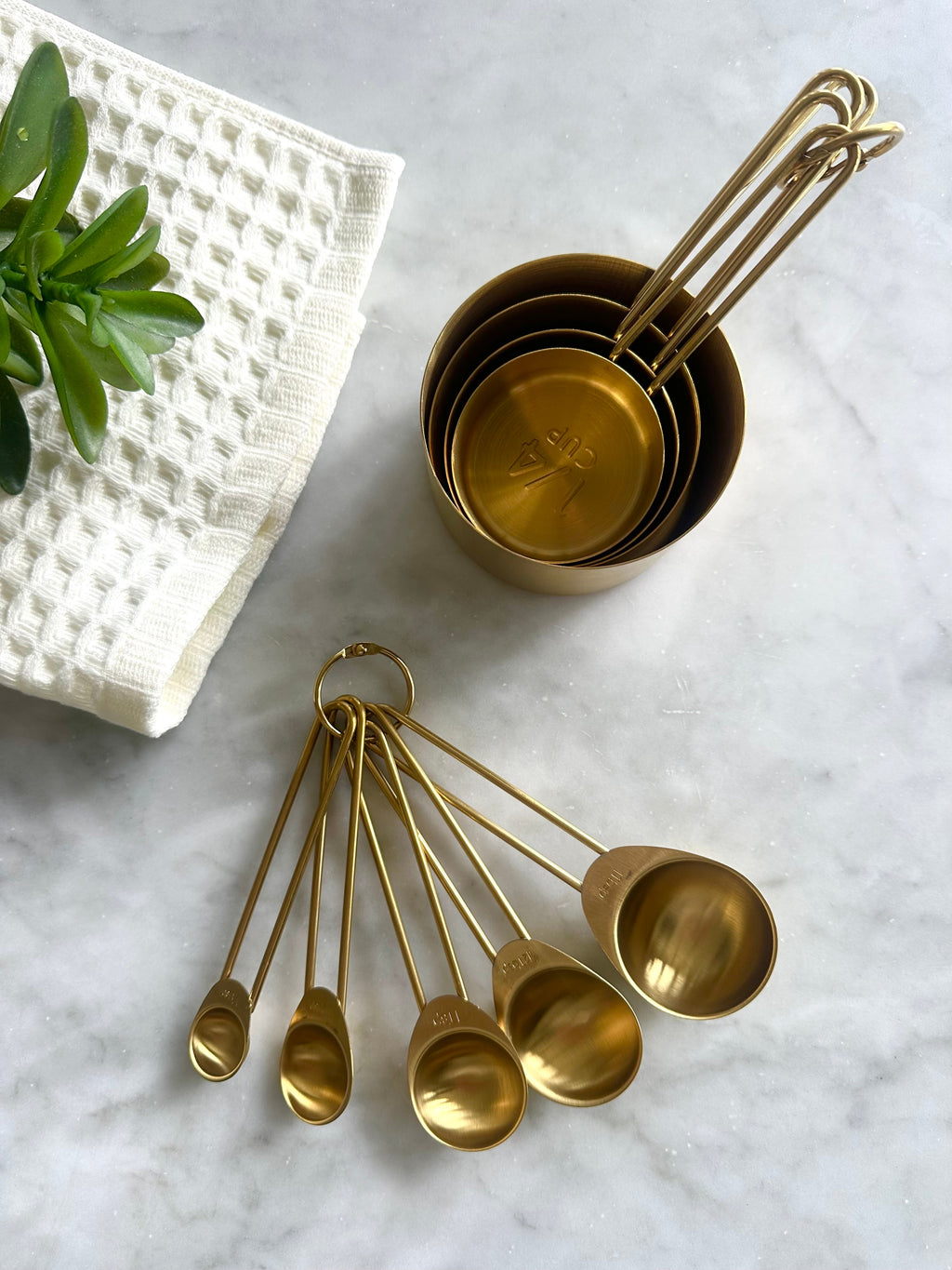 Overhead view of nested gold measuring cups and a fan of measuring spoons
