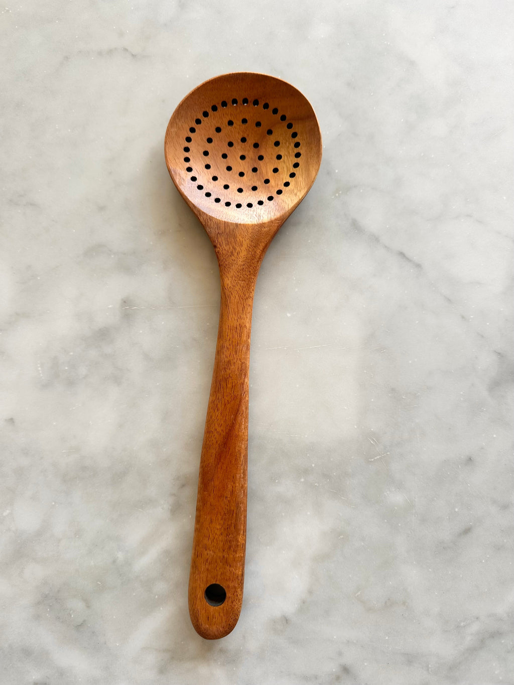 Teak wood slotted spoon with a round perforated bowl and hanging hole