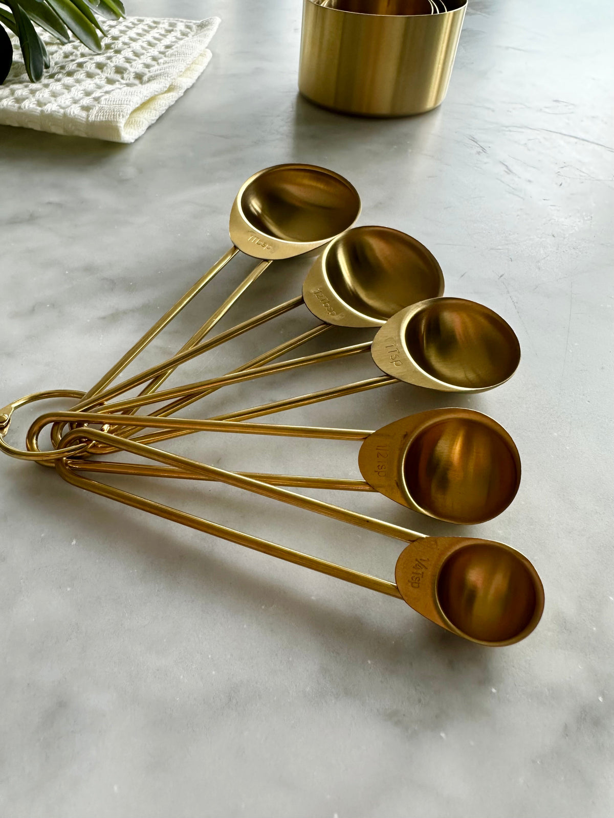 Five gold measuring spoons fanned out to show their different sizes