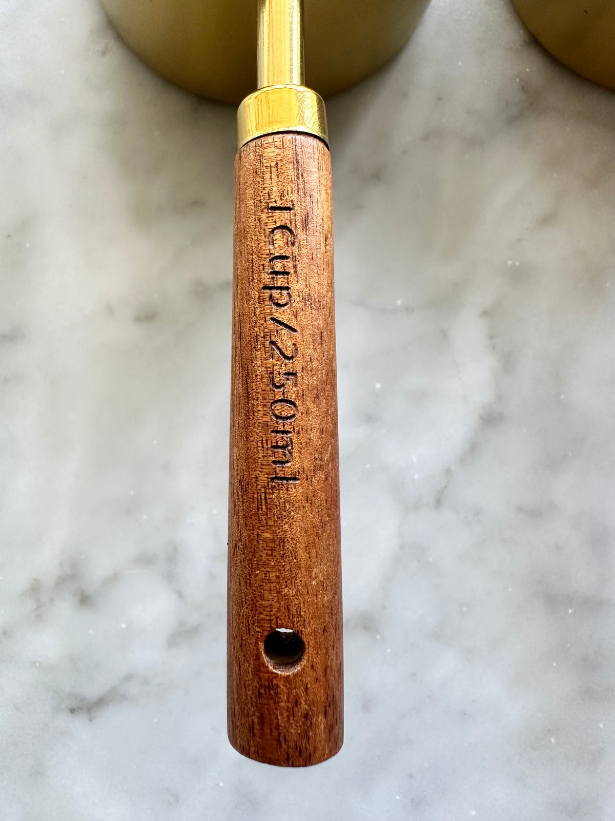 Close-up of a wooden measuring cup handle marked 1 cup and 250 mL