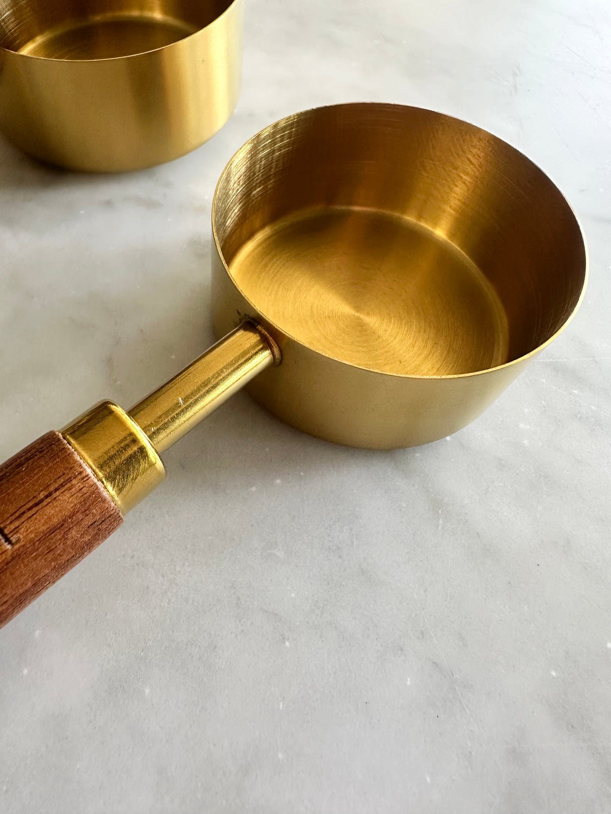 Interior view of a gold measuring cup attached to a wooden handle