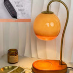 Orange wax melt lamp with a curved stand and an inset showing timer and brightness controls