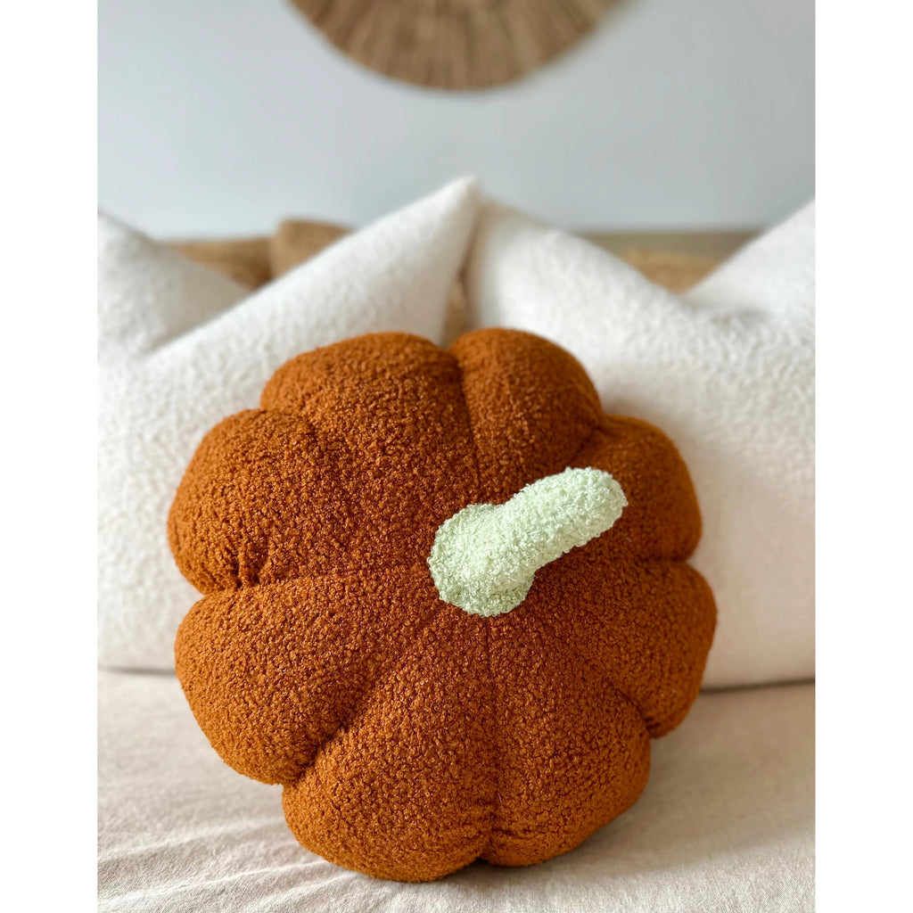 Close-up of an orange sherpa pumpkin pillow on a white cushion