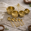 Nine-piece gold measuring cup and spoon set arranged on a kitchen counter