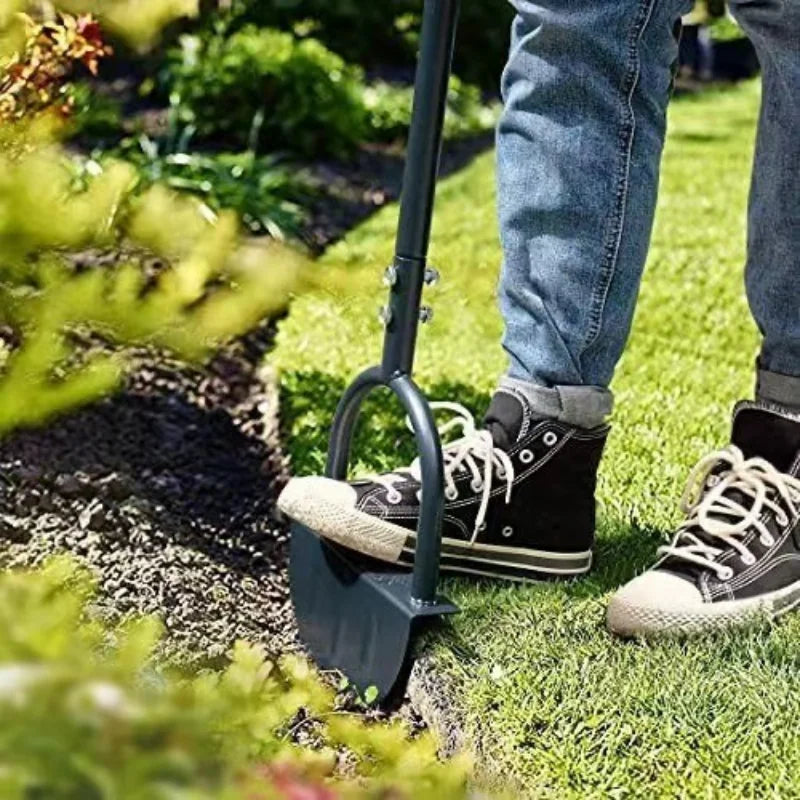 Foot pressing on a manual lawn edger at the edge of a garden bed