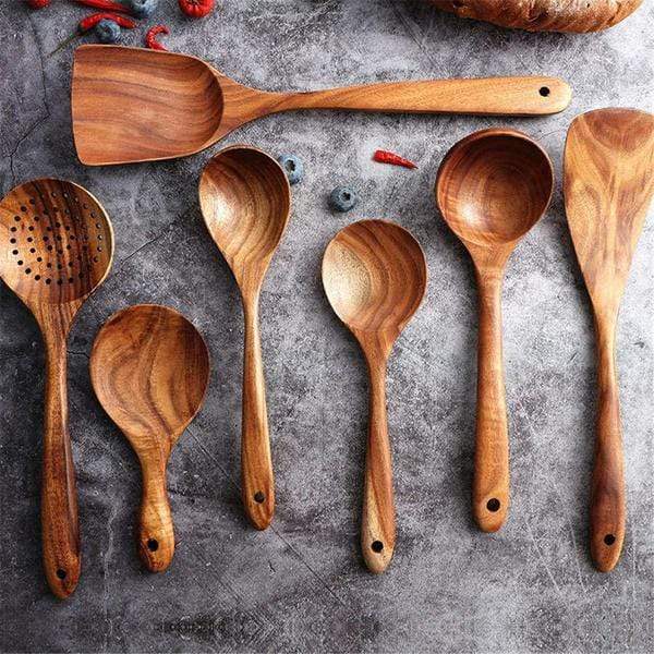 Teak wood spoons and turners laid out beside food ingredients