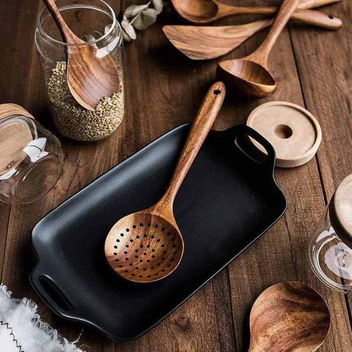 Slotted teak spoon resting over a rectangular cooking pan