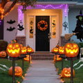 Solar pumpkin stake lights lining a decorated Halloween entrance