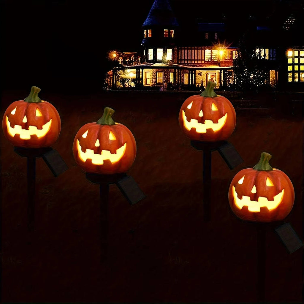 Four illuminated pumpkin stake lights against a dark background