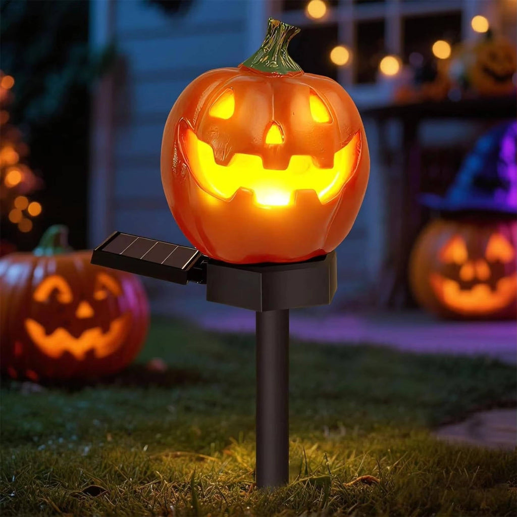 Close-up of a glowing pumpkin light on a black ground stake