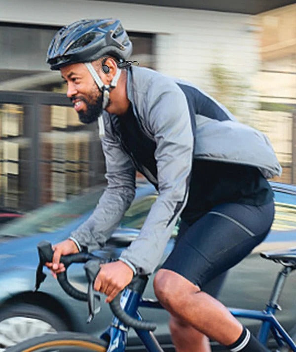 Cyclist wearing a helmet and open-ear headphones