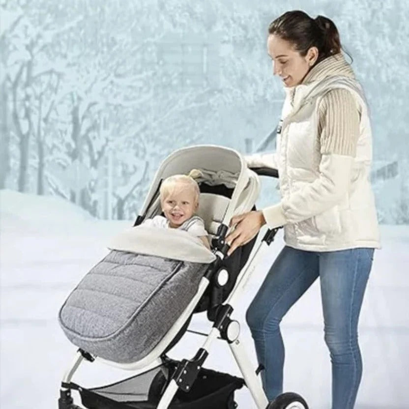 Baby in a gray footmuff during a winter stroller walk
