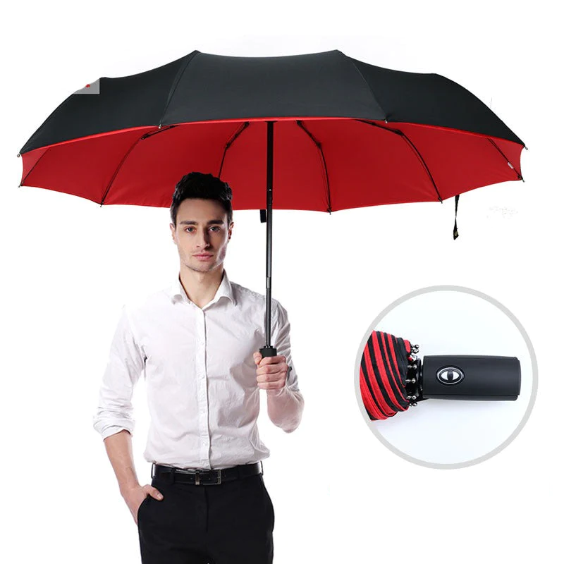 Open rain umbrella with black exterior and red interior held overhead