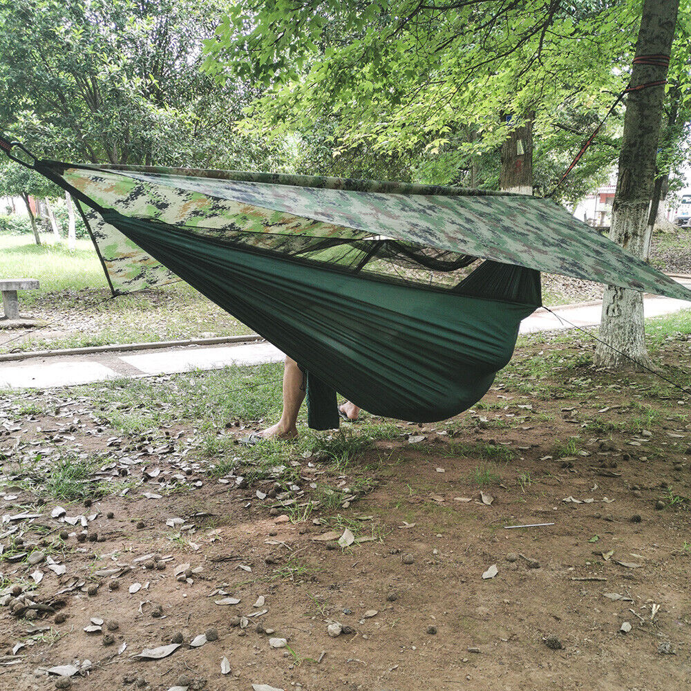 Camping hammock suspended beneath a camouflage rain fly