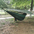 Camping hammock suspended beneath a camouflage rain fly