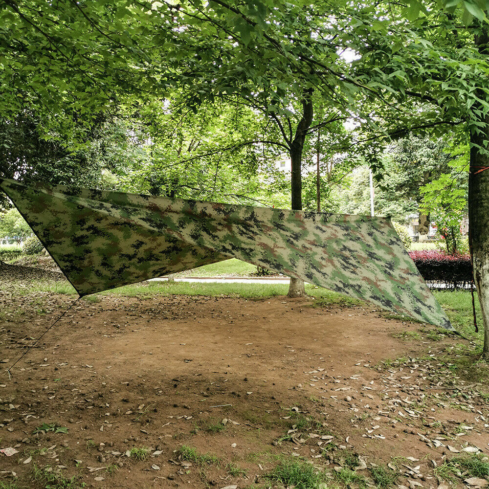 Camouflage rain fly pitched between trees at a campsite